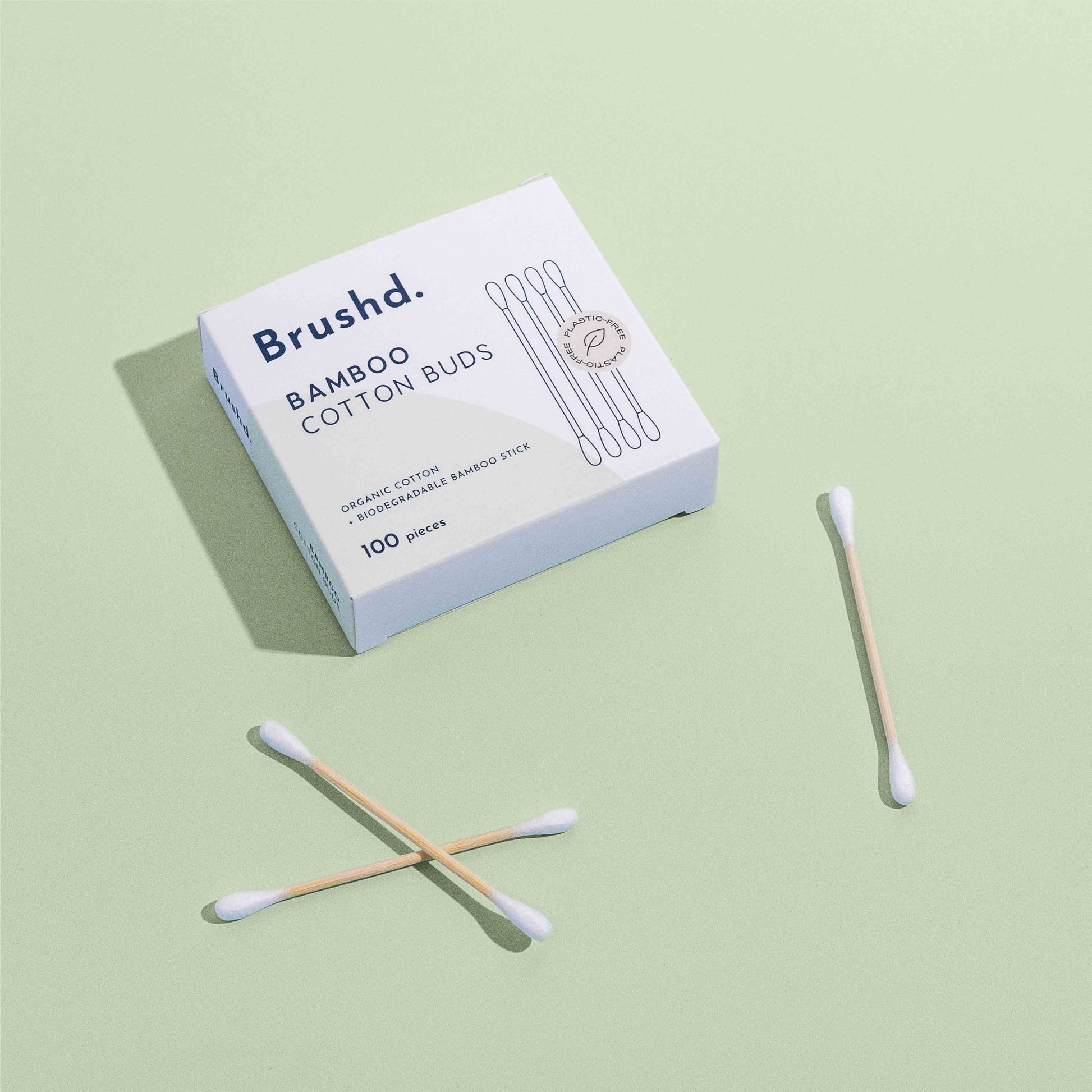 bamboo cotton buds by brushd on green background, birds eye view
