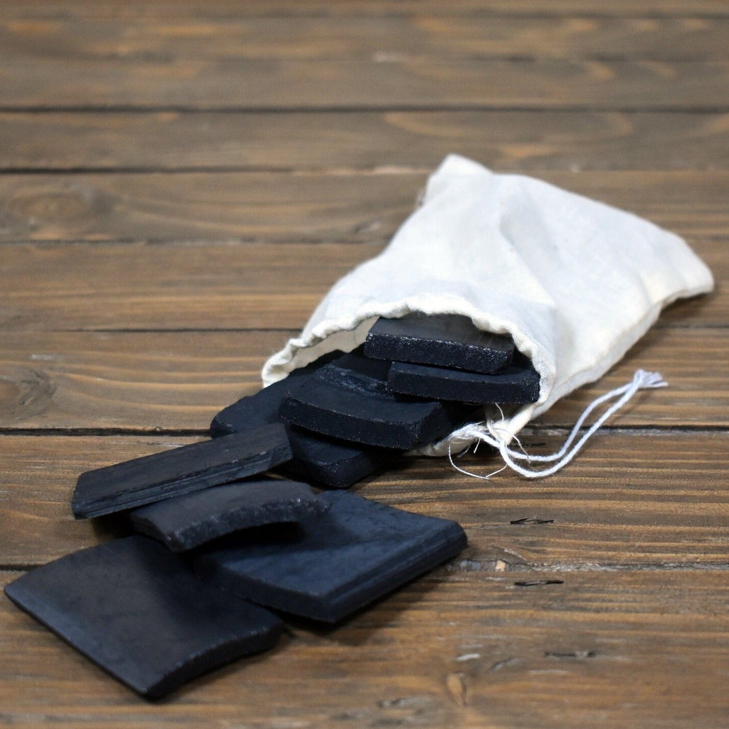 charcoal water filters spilling out of cotton zero waste bag, on wooden table