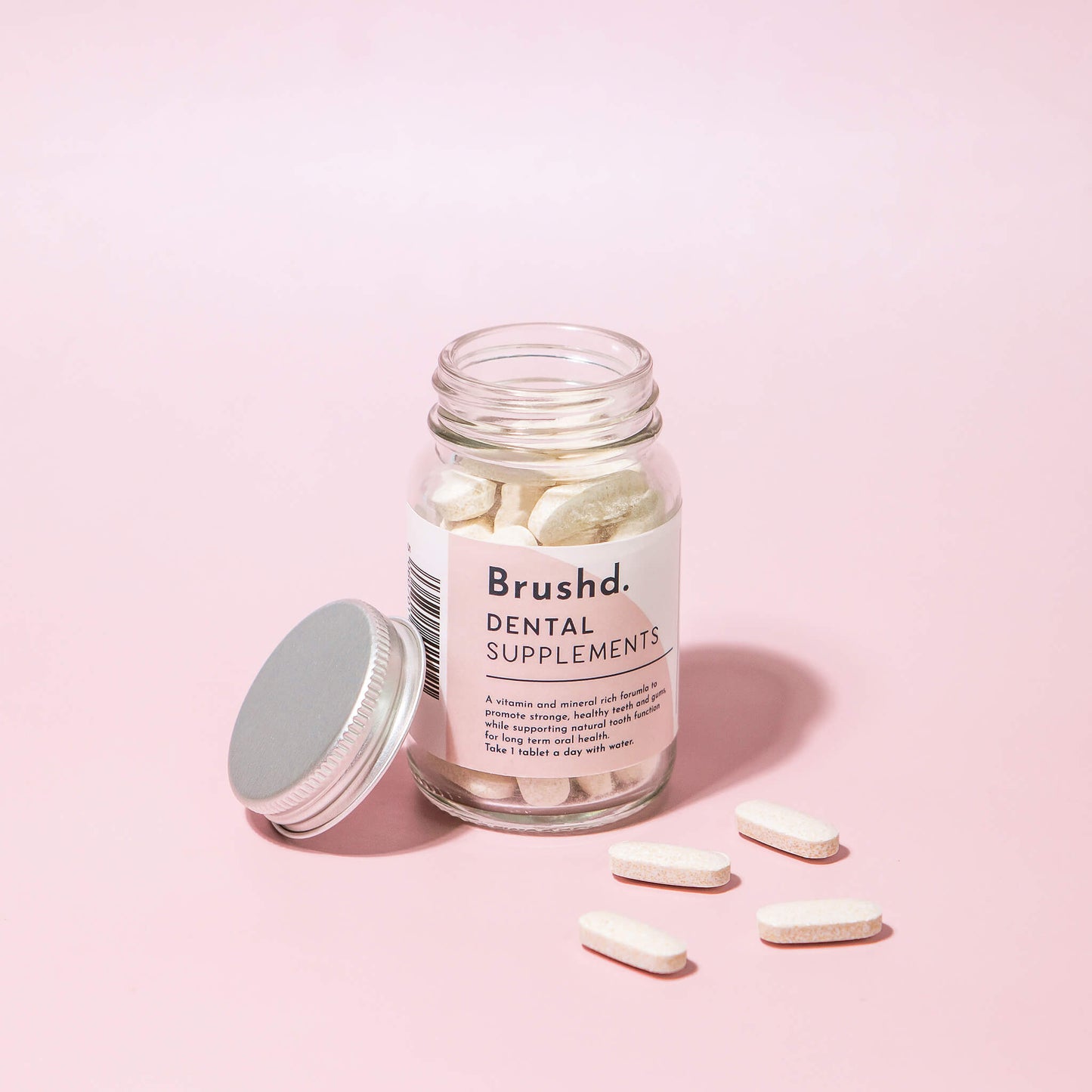 dental supplements in glass jar by brushd, pink background